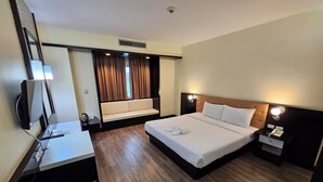 A hotel room with a bed, a desk, a TV, a sofa, and a window with curtains. - City Park Hotel (Nakhon Ratchasima)