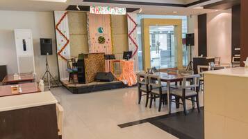 Un vestíbulo de hotel con un escenario para eventos, una recepción y un área de descanso.