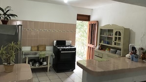 Une cuisine de taille réduite équipée d’une cuisinière, d’un réfrigérateur et d’un meuble avec des portes en verre.