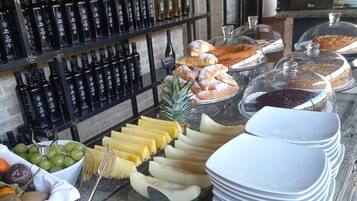 Un bufé con diversas frutas, quesos y pasteles.