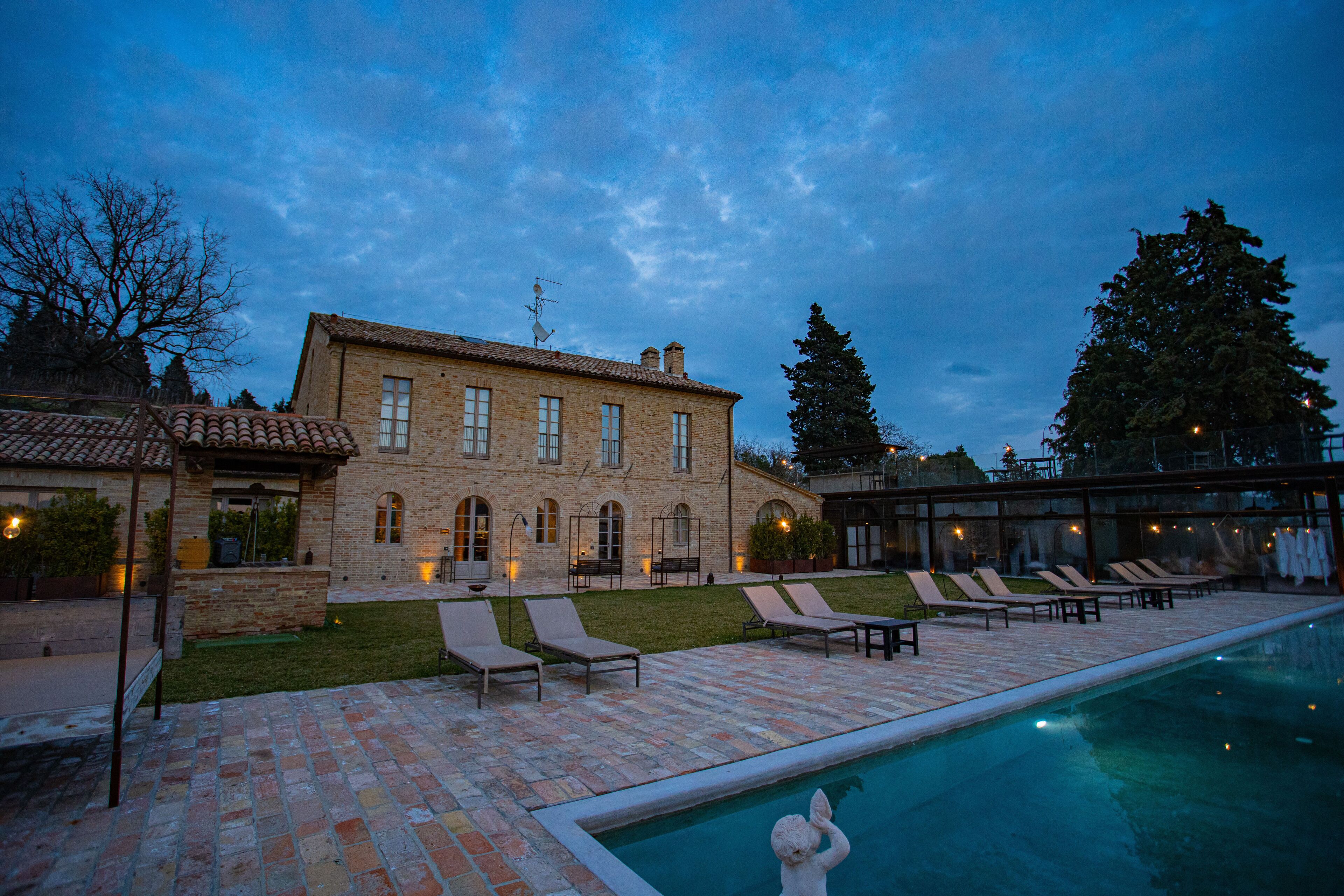 A stone building with a swimming pool, lounge chairs, and a well-maintained lawn.
