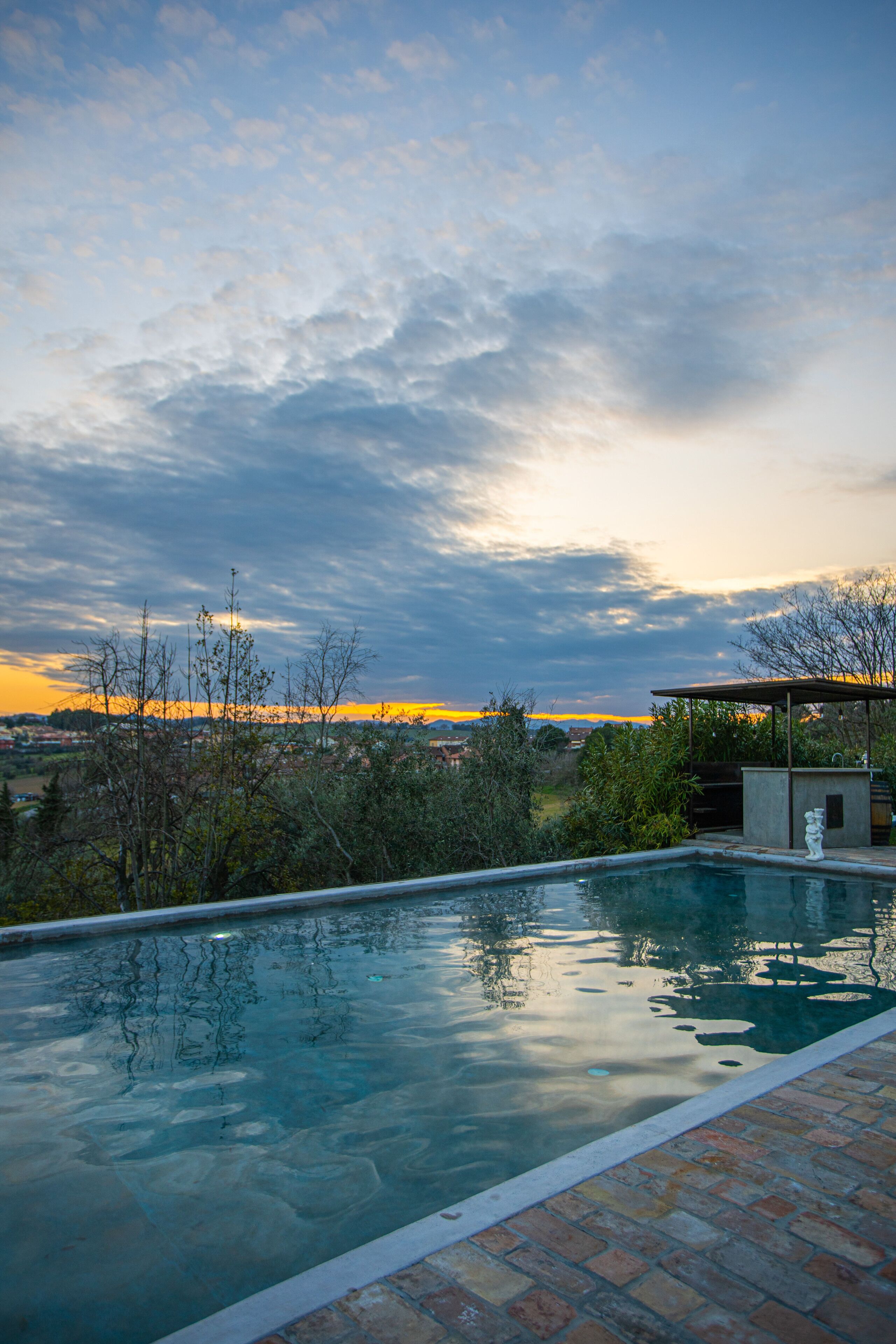 Piscina com vista para o pôr do sol e paisagem circundante.