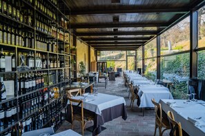 Un restaurante con una bodega de vinos, mesas dispuestas para comer y vistas al exterior.