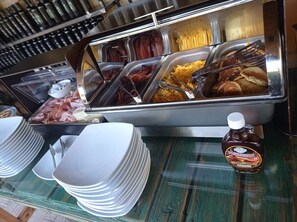 Ein Buffet mit verschiedenen Speisen, darunter Fleisch, Kartoffeln und Pfannkuchen.