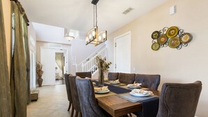 A dining area with a wooden table, grey upholstered chairs, and a chandelier.