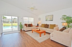 Relax in this inviting living room with a sliding door to an outdoor area featuring a pool and yard.