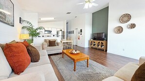 Een moderne woonkamer met een zithoek, een houten salontafel en een tv-meubel.