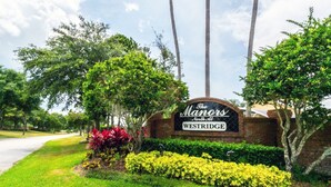 A sign for The Manor North at Westbridge, surrounded by lush greenery and palm trees. - Beautifully updated three bedroom, two bath pool home with spa and games room! (Davenport)