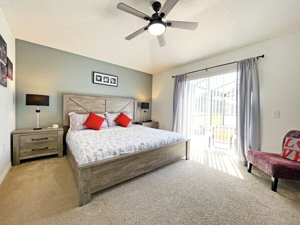 A bedroom with a bed, nightstands, a ceiling fan, a window with curtains, and a chair. - Beautifully updated three bedroom, two bath pool home with spa and games room! (Davenport)