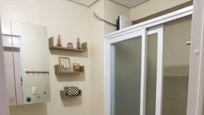 Kylpyhuone, jossa on wc, pesuallas ja lasinen suihkuseinä.