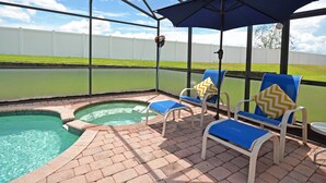 An outdoor pool area with a covered seating area, a basketball hoop, and a view of a green lawn and white fence. - Home from home! Updated - private pool & hot tub - gated resort (Clermont)