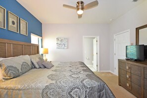 Cozy retreat with a large bed, ceiling fan, and mounted TV.