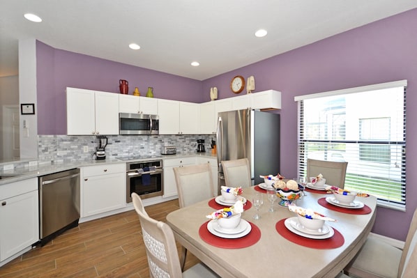Enjoy a meal in this stylish kitchen and dining area, featuring a modern design and a vibrant purple accent wall.