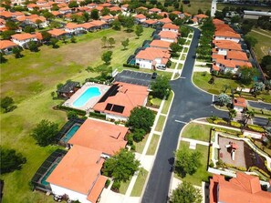 Residential neighborhood with houses featuring red-tiled roofs and green spaces.