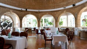 Un restaurante con arcos de ladrillo, mesas blancas y sillas marrones.
