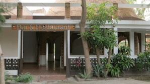 Un bar y restaurante con estructura de cúpula de ladrillo, mesas al aire libre y acceso cubierto.