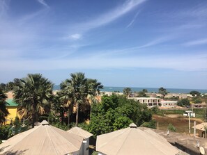 A view of a coastal area with palm trees, buildings, and a clear sky.