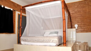Una cama con dosel, una mesita de noche y una pared de ladrillo.