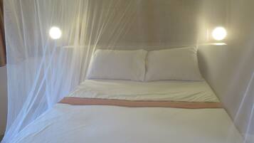 A bed with a canopy, two bedside lamps, and a wooden headboard.