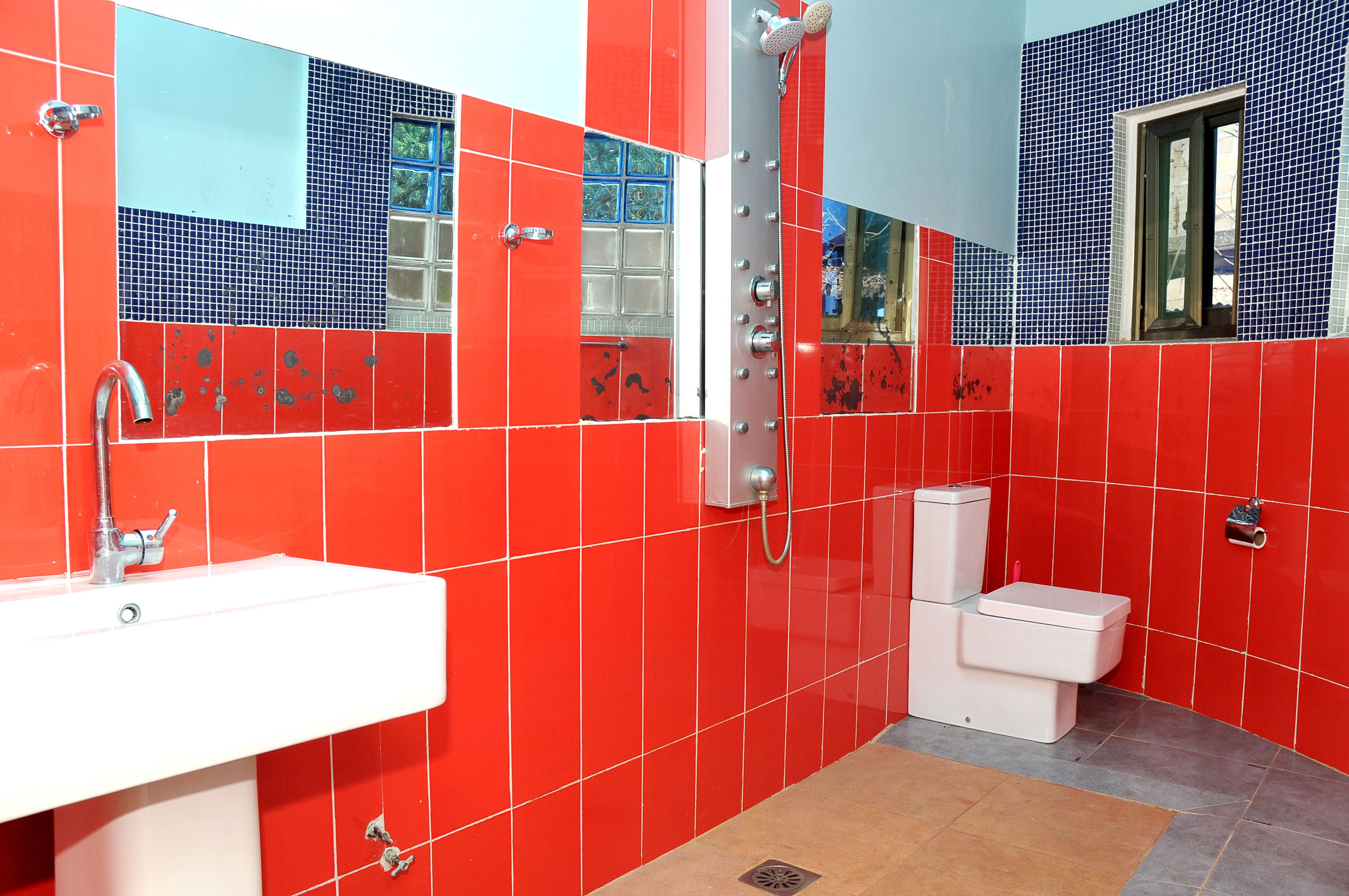 Een badkamer met rode en blauwe tegels, een wit wastafel en een toilet.