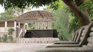 Un espacio al aire libre cubierto con estructura de techo metálico y una serie de escalones que conducen a la entrada de un edificio.