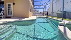 A swimming pool with a glass enclosure, a door, and a chair outside. - Superior family vacation home (Haines City)