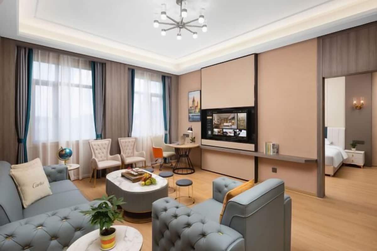 Une chambre d’hôtel moderne équipée d’un canapé, de fauteuils, d’une table basse, d’un téléviseur et d’un lit.
