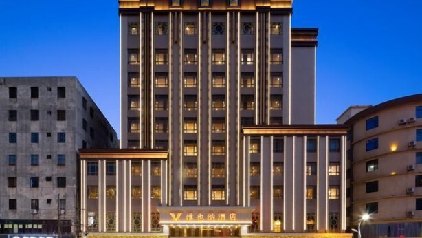 Ein mehrstöckiges Hotel mit markanter, vertikaler Säulenarchitektur, beleuchteter Beschilderung und freiem Blick auf den Eingang.