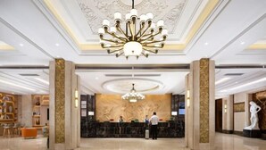 Eine Hotelhalle mit einer prächtigen Kronleuchter, einer Marmor-Rezeption und einer Statue.