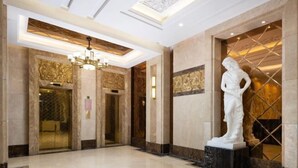 Eine großzügige Lobby mit Marmorboden, einem großen Kronleuchter und einer Statue einer Frau.