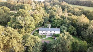 A two-story house surrounded by dense forest.
