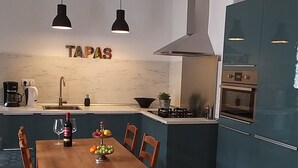 A modern kitchen with a wooden dining table, blue cabinets, and a tiled floor with geometric patterns. - Casa Los Molinos with heated pool in the middle of nature (Montefrio)