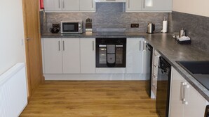 A modern kitchen with white cabinets, a microwave, a coffee maker, and a dishwasher. - Bright modern apartment (Keiss)