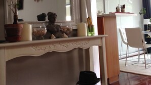A room with a fireplace, a mirror, and a dining area with a chair and table. - Sweet Home Paris 12ème in lush greenery. Well located (Paris)