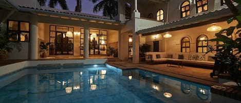 Una piscina al aire libre, sombrillas, sillones reclinables de piscina