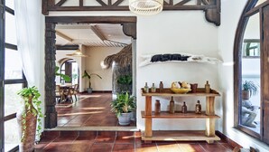 A hallway with a wooden bench, a shelf with decorative items, and a large window with a view of the outside. - Paradise Beach Lodge (Cóbano)