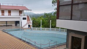 A swimming pool with a checkered floor, a staircase leading to a balcony, and a view of mountains in the background. - Hunky Dory Resort (Dhar Kalan)
