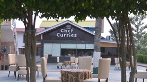 An outdoor seating area with tables and chairs in front of a building with a sign reading "Chef Curries". - Hunky Dory Resort (Dhar Kalan)