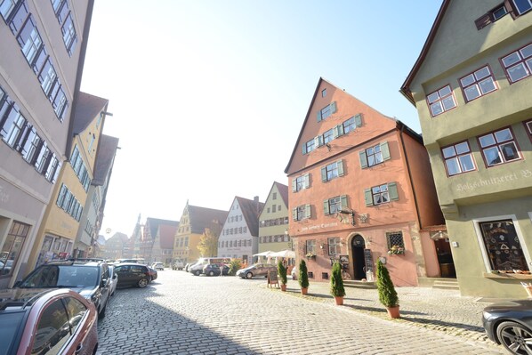 A cobblestone street lined with traditional European buildings, some with visible signage. - Eisenkrug (Dinkelsbuehl)