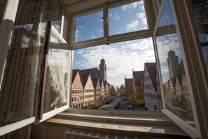 A window with a view of a street lined with traditional buildings and a church tower. - Eisenkrug (Dinkelsbuehl)
