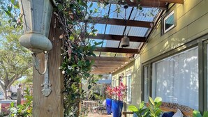 A covered outdoor area with a wooden pergola, potted plants, and a bench.