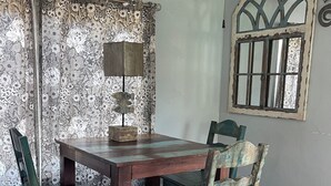 A dining area with a wooden table and chairs, a ceiling fan, and a window with a decorative frame.