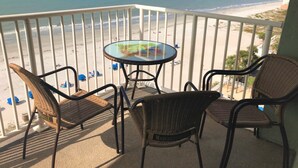 A balcony with wicker chairs and a glass table overlooking a beach. - DIRECT BEACHFRONT - PENTHOUSE CORNER UNIT!!  Totally Renovated! (Indian Shores)