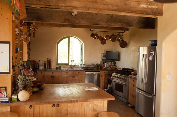A kitchen with wooden cabinets, a large island, stainless steel appliances, and a window providing natural light.