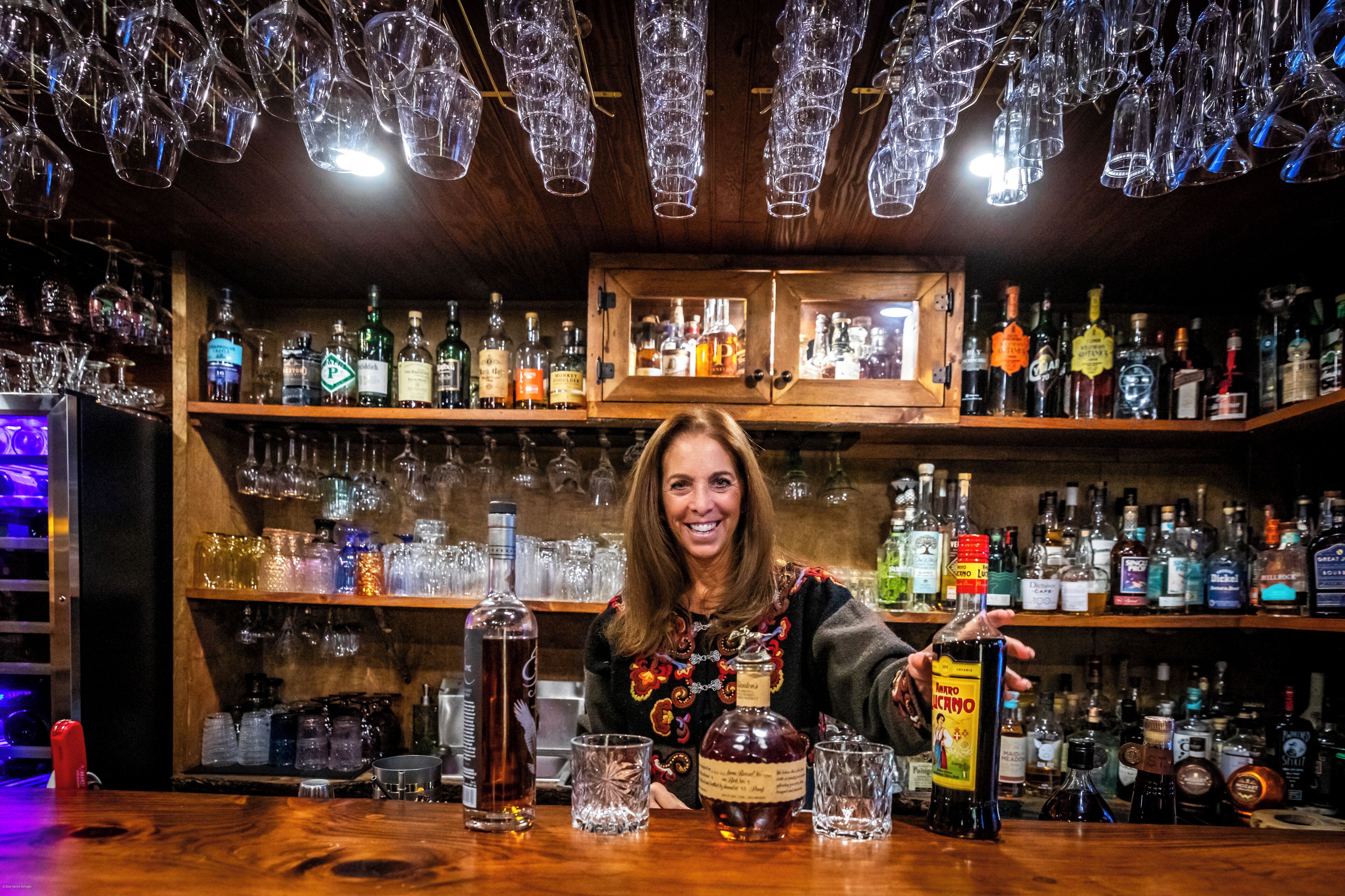 Baari, jossa on hyllyt täynnä alkoholijuomapulloja ja laseja.