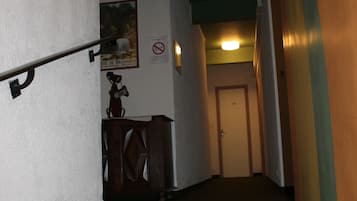 Un couloir étroit avec un escalier menant à une porte au fond.