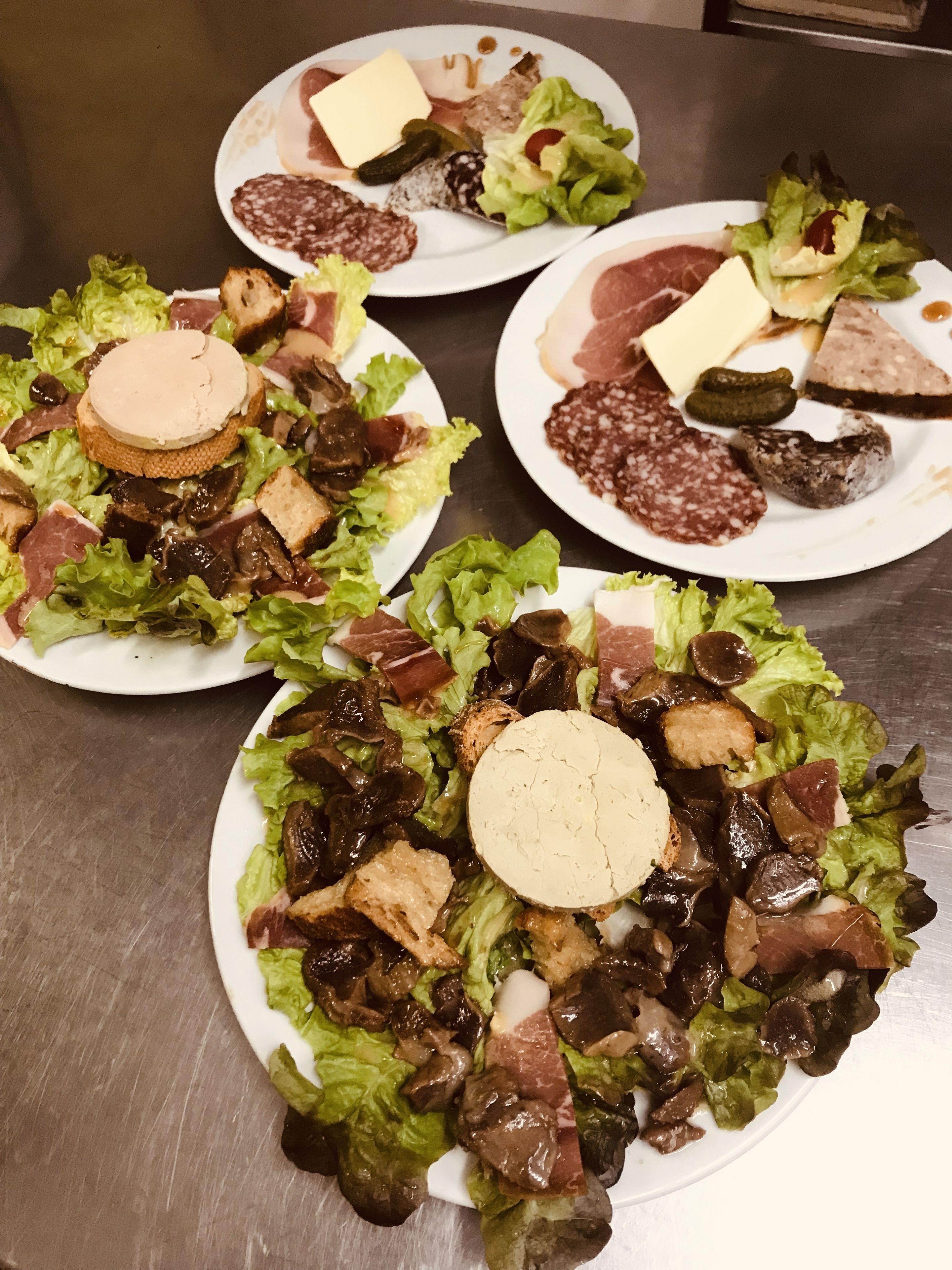 Ein Tisch mit verschiedenen Speisen, darunter Salate und verschiedene Fleischsorten.