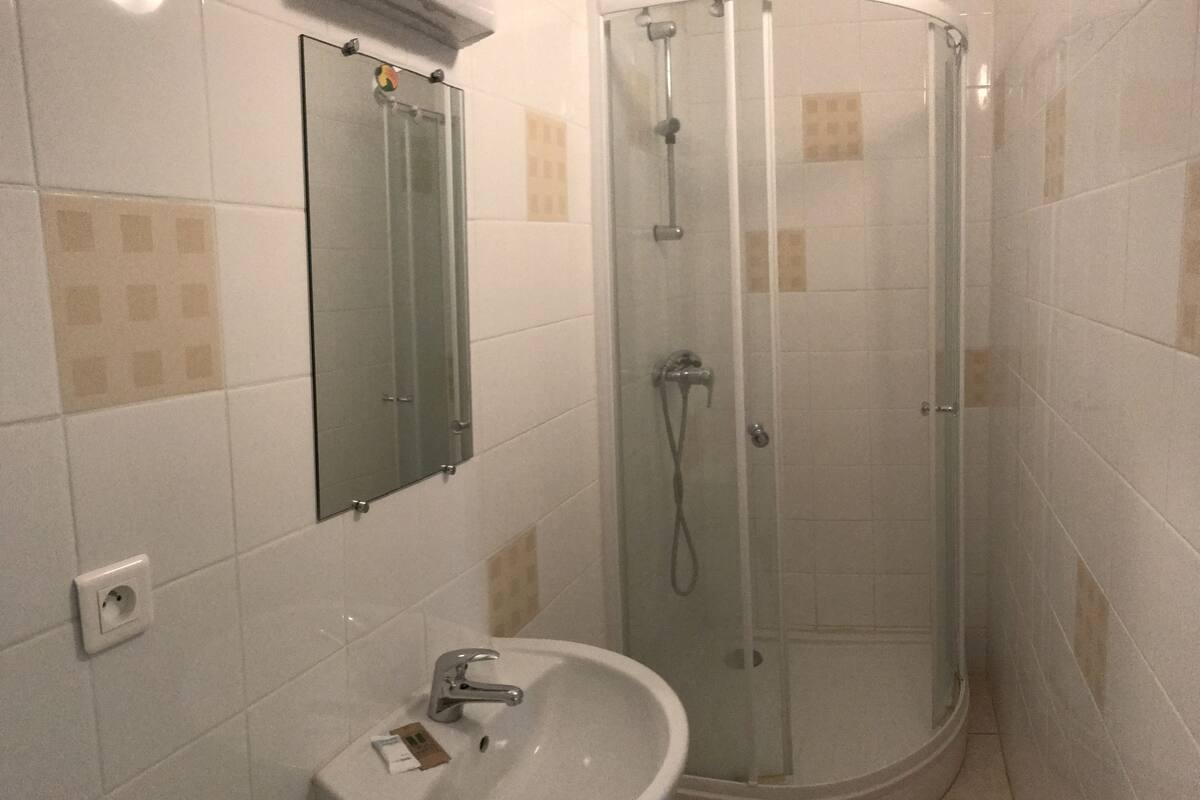 A bathroom with a glass-enclosed shower, a sink with a mirror above it, and tiled walls.
