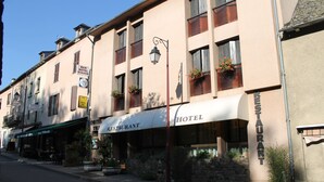 A hotel with a restaurant on the ground floor, featuring a stone facade, multiple windows with flower boxes, and outdoor seating. - L'Agapanthe (Pont-de-Salars)