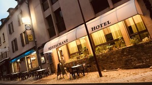 A hotel with a restaurant on the ground floor, outdoor seating, and a stone wall with plants. - L'Agapanthe (Pont-de-Salars)